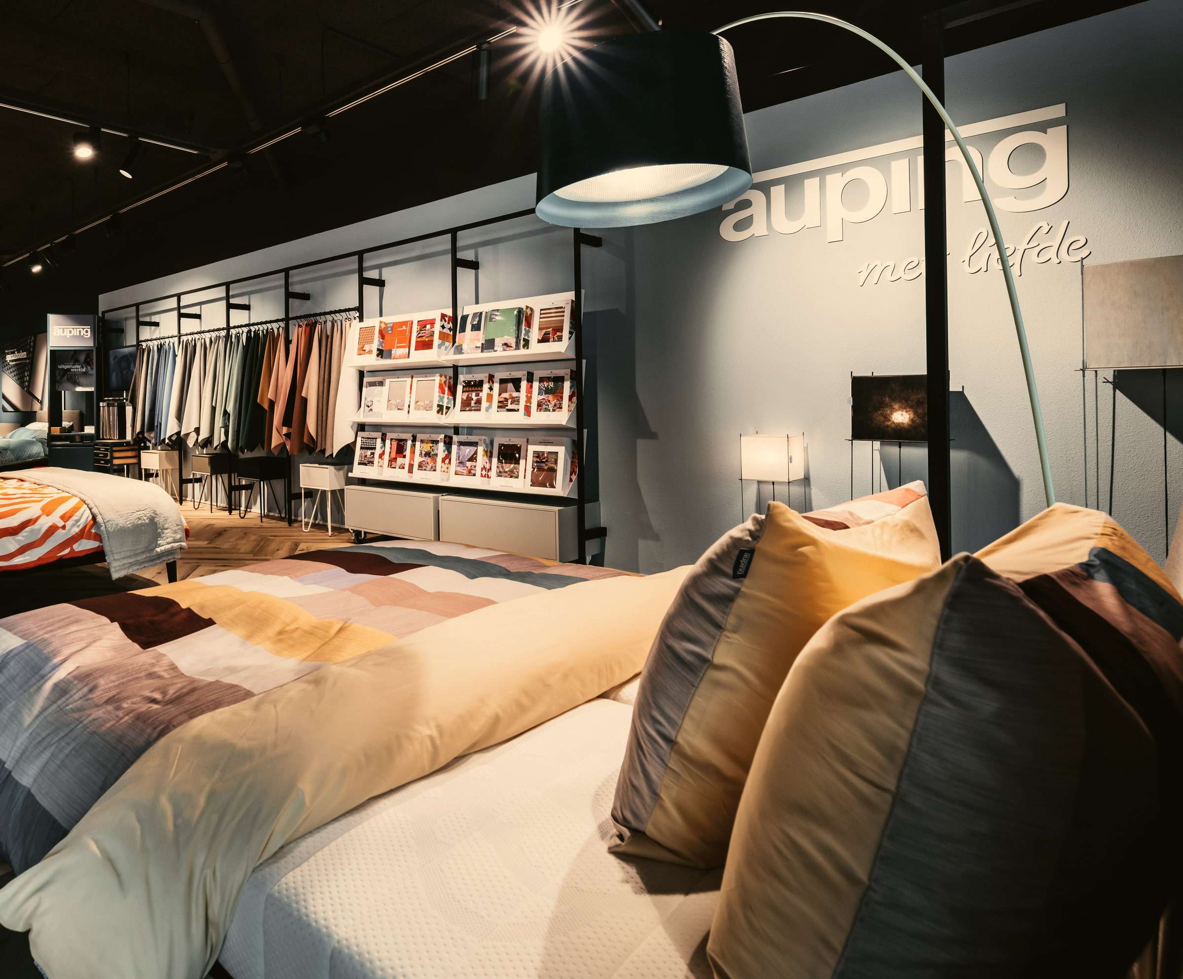De Auping Studio in de showroom van Wielinga & Tabbers: een opgemaakt bed met kussens, daarachter rekken met beddengoed